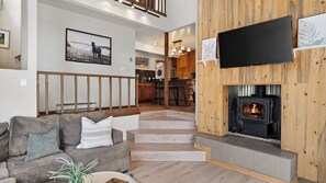 Ein Wohnzimmer mit Kamin, einer Couch und einer Treppe, die in eine Küche führt.