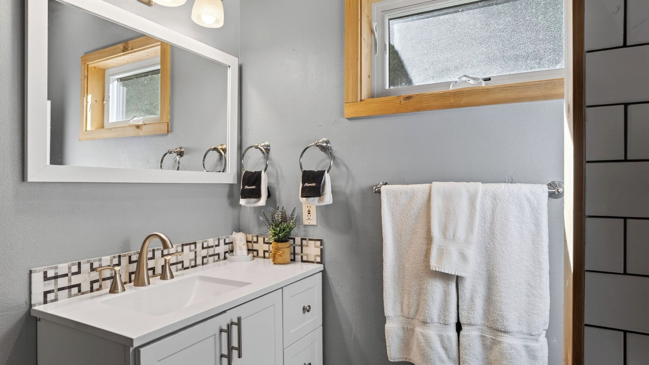 A bathroom with a white sink, a mirror, and a towel rack.