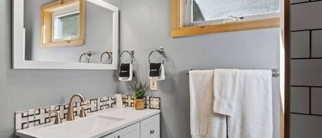 A bathroom with a white sink, a mirror, and a towel rack.