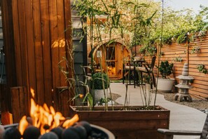 A wooden deck with a fire pit, outdoor seating, and a garden area with plants and a stone lantern. - Zen Tiny Haus Oasis near UO (Eugene)