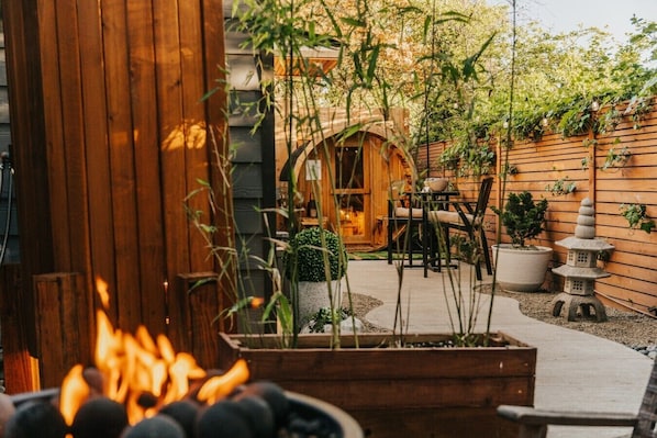 Eine Holzterrasse mit Feuerstelle, Gartenmöbeln und einer Steinhlaterne.