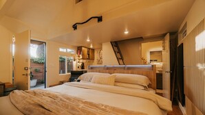 Ein Schlafzimmer mit Bett, Schreibtisch, Stuhl, Heizkörper, Fenster und Tür.