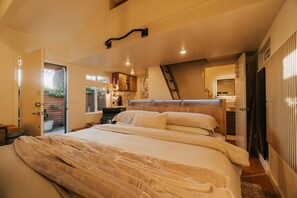 Ein Schlafzimmer mit Bett, Schreibtisch, Stuhl, Heizkörper, Fenster und Tür.
