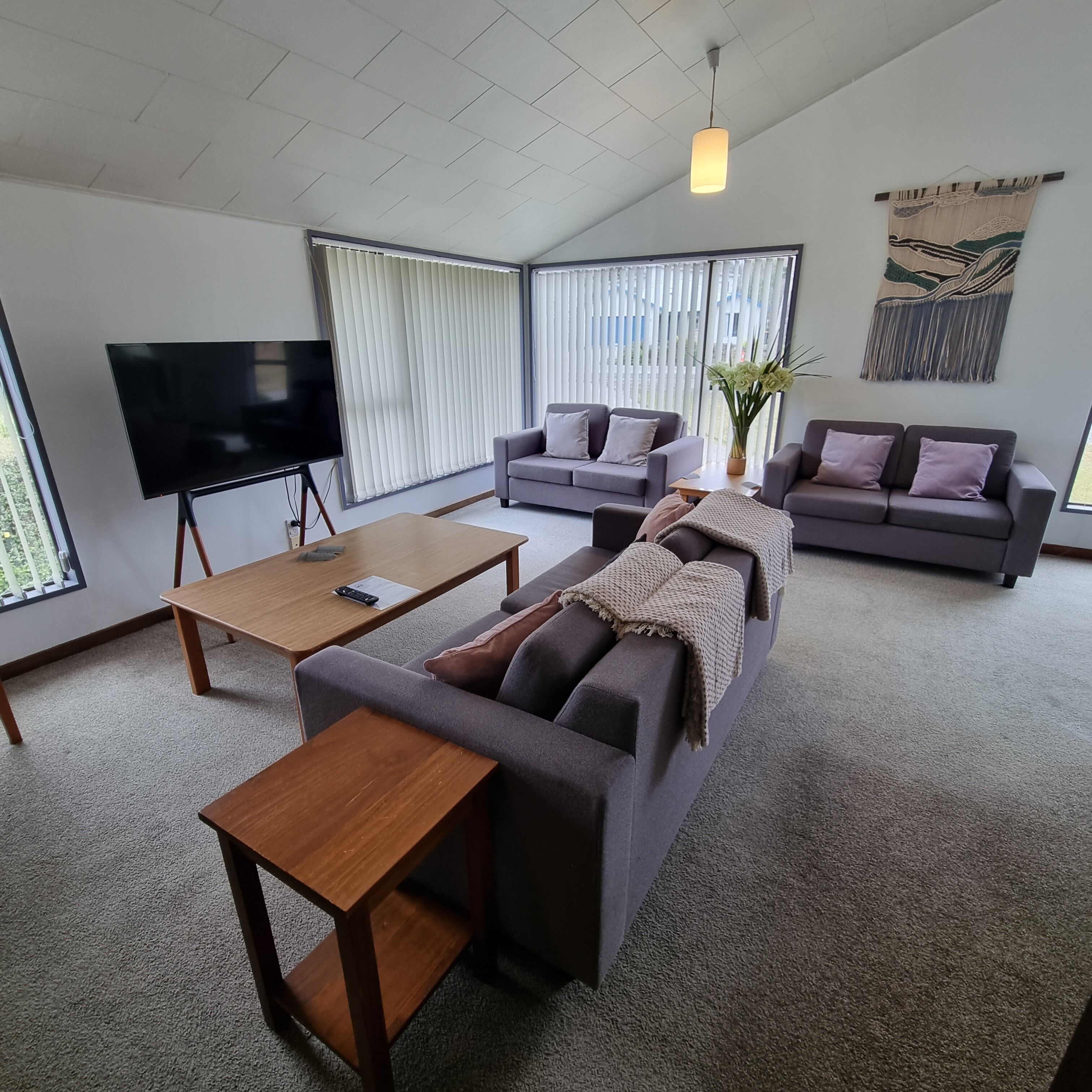 A modern living room with a sofa, a coffee table, a TV, and a large window.