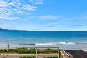 Blick auf die Küste mit klarem Himmel, einem Zaun und einer Straße, die zum Strand führt.