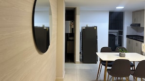 Una cocina moderna con comedor, que incluye un espejo grande, un refrigerador y una mesa con sillas.