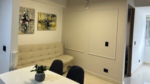 Una sala de conferencias con una mesa blanca, dos sillas, un sofá y dos pinturas abstractas en la pared.