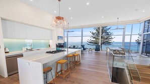A modern kitchen with a central island, large windows, and a view of the ocean. - Reefwatch, Wall of Glass, Endless Ocean Views (Encounter Bay)