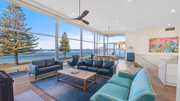 A modern living room with large windows, a ceiling fan, and a view of the sea. - Reefwatch, Wall of Glass, Endless Ocean Views (Encounter Bay)