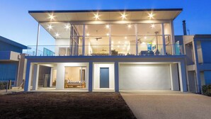 A modern two-story house with a covered balcony, a garage, and a visible interior with a bed and a chair. - Reefwatch, Wall of Glass, Endless Ocean Views (Encounter Bay)