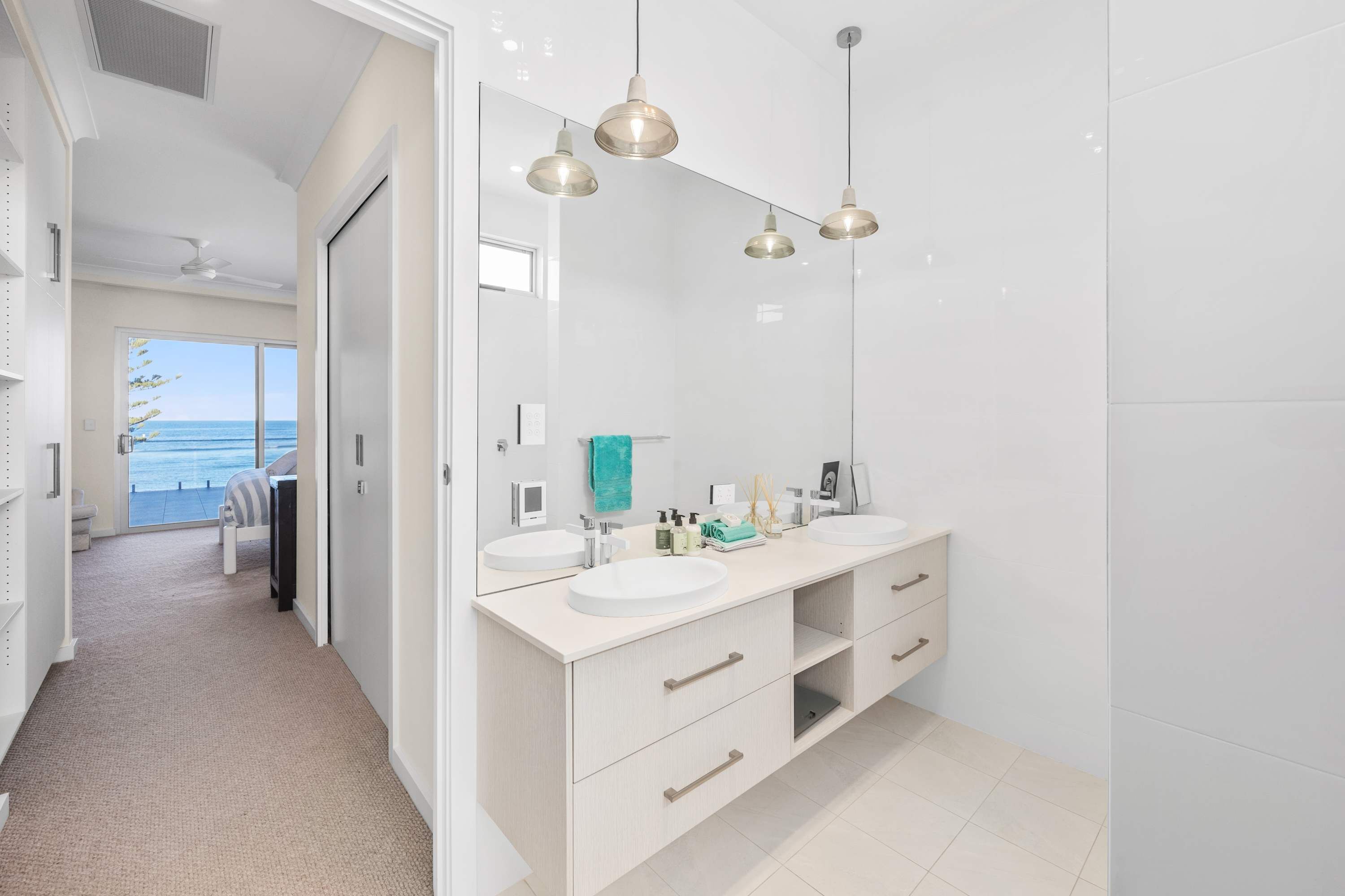 Un baño moderno con dos lavamanos, un espejo grande e iluminación colgante.