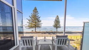 A balcony with a white table and two chairs, overlooking a beach with two tall trees and the ocean. - Reefwatch, Wall of Glass, Endless Ocean Views (Encounter Bay)