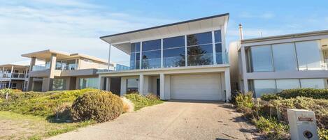 Un bâtiment moderne doté de grandes fenêtres, d’un garage et d’une allée pavée.