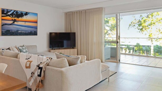 Een moderne woonkamer met een bank, televisie en een balkon met uitzicht.