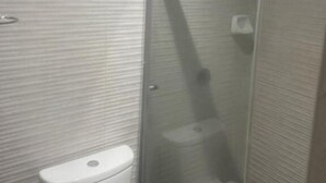 Een badkamer met toilet, douchecabine en betegelde wanden.
