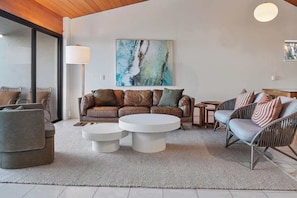 A modern living room with a leather sofa, two round coffee tables, and wicker chairs.
