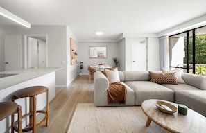 A modern living space with a kitchen, dining area, and a large window. - Chic Noosa Riverside Apt with Great Facilities (Noosa Region)
