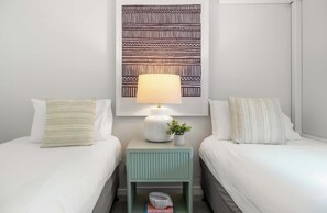 A hotel room with two beds, a nightstand with a lamp, a decorative wall piece, and a small plant. - Chic Noosa Riverside Apt with Great Facilities (Noosa Region)