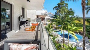 A modern house with a balcony overlooking a swimming pool, surrounded by lush greenery. - Resort Unit, Heated Pool, AC, Walk to Main Beach (Noosa Region)
