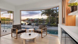 A modern living room with a pool view, large windows, and minimalist furniture. - Luxurious Impeccably Styled Waterfront Noosa Home (Noosa Region)