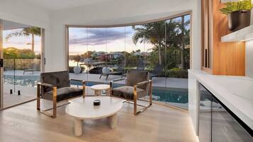 A modern living room with a pool view, large windows, and minimalist furniture.