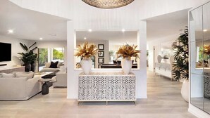 A spacious living area with a modern sofa set, a patterned console table, and a large chandelier. - Luxurious Impeccably Styled Waterfront Noosa Home (Noosa Region)