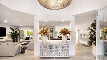 A spacious living area with a modern sofa set, a patterned console table, and a large chandelier.
