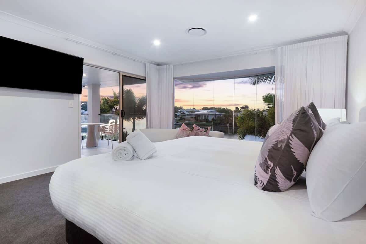 A modern hotel room with a large bed, a flat-screen TV, and a balcony with a city view.