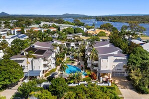 A residential area with modern houses, a swimming pool, and a marina in the background. - Montpellier Riverside Apartment with Heated Pool (Noosa Region)