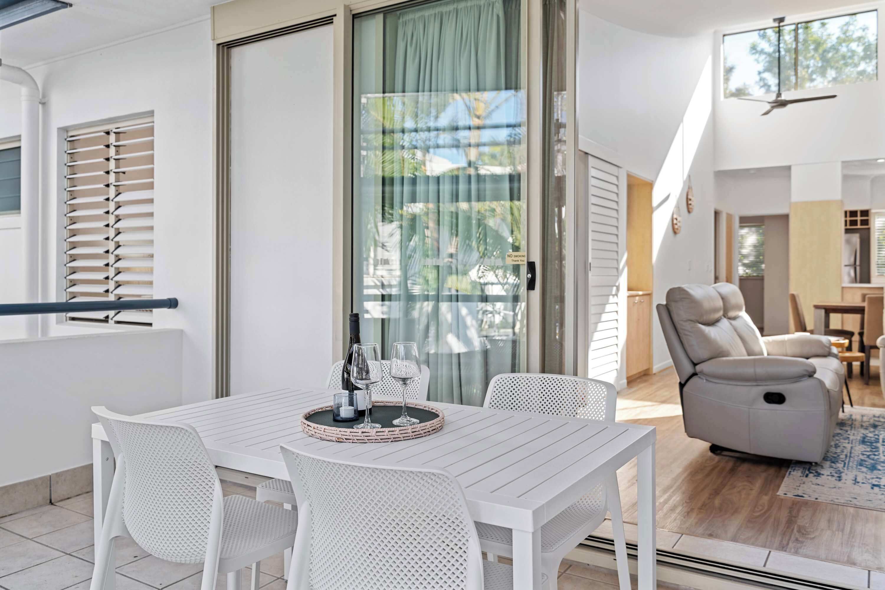 Ein modernes Wohnzimmer mit einem weißen Tisch, weißen Stühlen, einem Sofa und einem Deckenventilator.