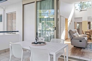 A modern living room with a white table, white chairs, a sofa, and a ceiling fan. - Montpellier Riverside Apartment with Heated Pool (Noosa Region)