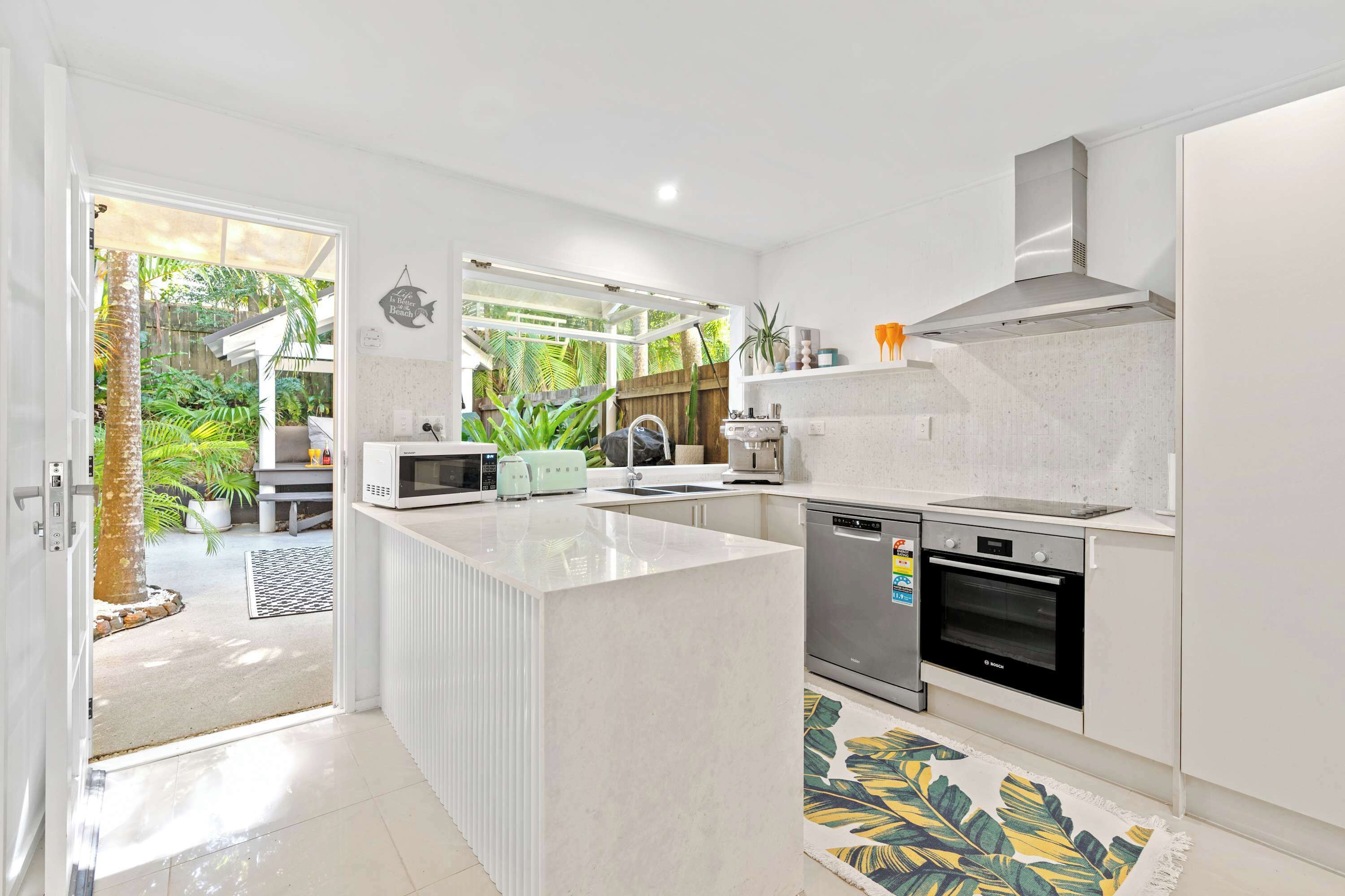 A modern kitchen with a central island, a built-in oven, and a microwave.