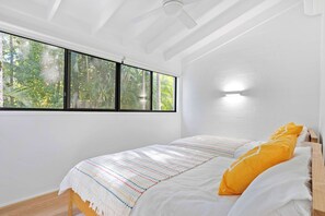 A bedroom with a bed, a window with a view of greenery, and a ceiling fan. - Yarraga Tropical Escape with Pool & Private Rooftop (Noosa Region)