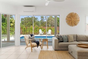 A modern living room with a sofa, a chair, a small table, and a decorative wall piece. - Southwind in Sunrise (Noosa Region)