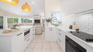 Una cocina moderna con armarios blancos, una estufa negra y una zona de comedor con televisor.