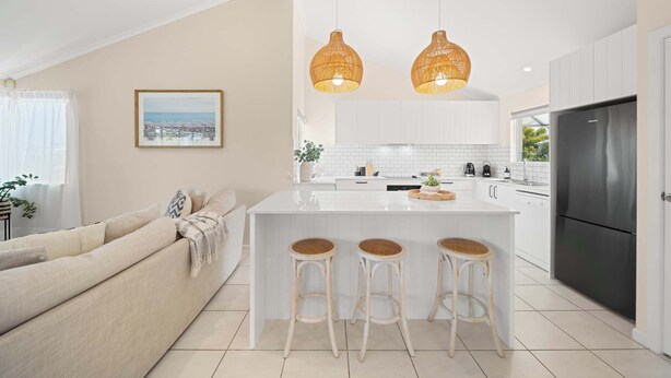 Una cocina moderna con una isla central, armarios blancos y un refrigerador negro.