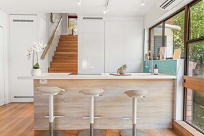 Eine moderne Küche mit einer Holztreppe, weißen Schränken und einem großen Fenster.