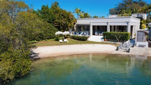 A modern house with a pool, surrounded by lush greenery and a clear sky. - Quintessential Noosa Waterfront Home Heated Pool (Noosa Region)