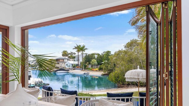 A balcony with a view of a swimming pool, lounge chairs, and a white vase. - Quintessential Noosa Waterfront Home Heated Pool (Noosa Region)
