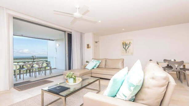 A modern living room with a sofa, coffee table, and a balcony with outdoor seating. - "The Outlook" Views, Pool & Walk to Main Beach (Noosa Region)
