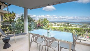 A balcony with a glass table and chairs, overlooking a cityscape and greenery. - "The Outlook" Views, Pool & Walk to Main Beach (Noosa Region)