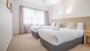 A hotel room with two beds, a ceiling fan, a large window with curtains, and a light wall-mounted lamp. - "The Outlook" Views, Pool & Walk to Main Beach (Noosa Region)