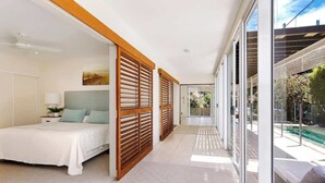 A modern hotel room with a bed, a nightstand, a large window, and a view of the outdoors. - Noosa Luxe Coastal Home with Panoramic Views (Noosa Region)