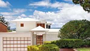 A modern two-story house with a garage, a small porch, and a well-maintained lawn. - Noosa Luxe Coastal Home with Panoramic Views (Noosa Region)