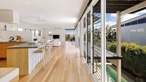 A modern kitchen with a long counter, white cabinetry, and a view of the outdoors. - Noosa Luxe Coastal Home with Panoramic Views (Noosa Region)