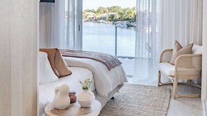 Une chambre à coucher avec un lit, une table de chevet et une vue sur un plan d’eau.