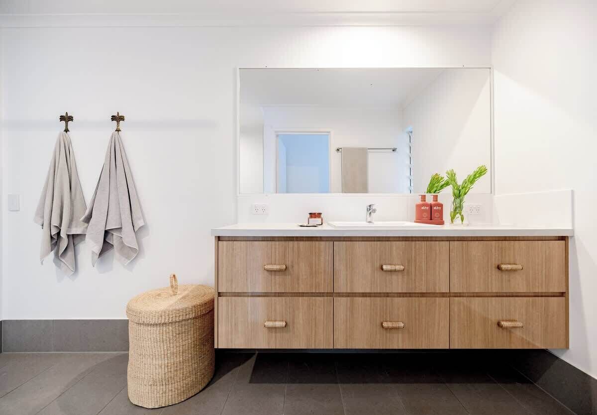 Un baño con tocador de madera, un espejo grande y dos toallas colgadas en ganchos.