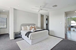 A modern bedroom with a large bed, a ceiling fan, and a view into the adjacent room. - Exclusive Waterfront Oasis w/ Private Beach & Pool (Noosa Region)