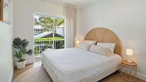 A bedroom with a large bed, a ceiling fan, a potted plant, and a view of the outdoors. - Modern, Stylish, Resort style Noosa River stay (Noosa Region)