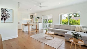 A modern living room with a sofa, coffee table, and a dining area with a table and chairs. - Modern, Stylish, Resort style Noosa River stay (Noosa Region)